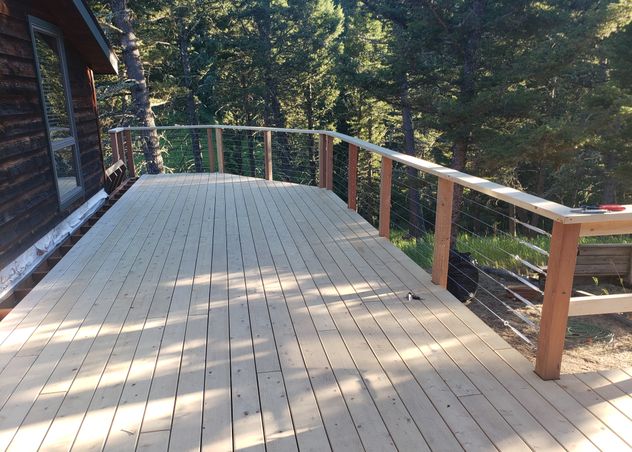 A beautiful cedar deck with wire railing in the bridger mountains by Hutch Construction